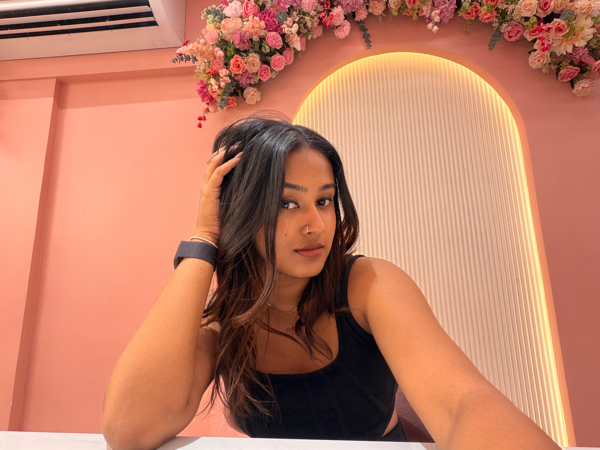 Aswathy in a black top against a warm arch backdrop